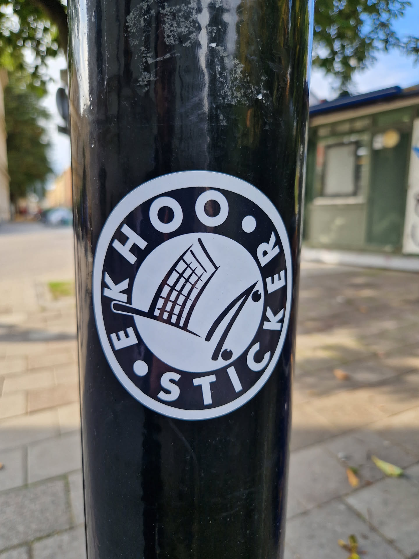 A black and white round sticker with the text "EEKHOO STICKER" arranged in a circle around a simple graphic of a shopping cart and what looks like a pair of tongs or similar.