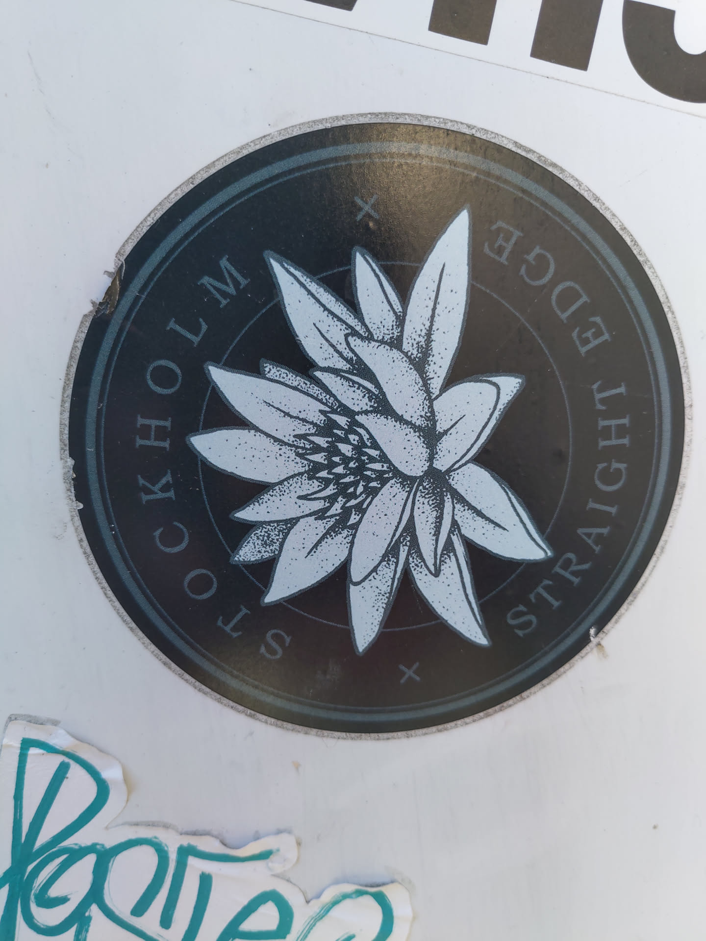 Round sticker with a flower graphic and text. The text says "Stockholm Straight Edge". The flower is stylized and detailed.