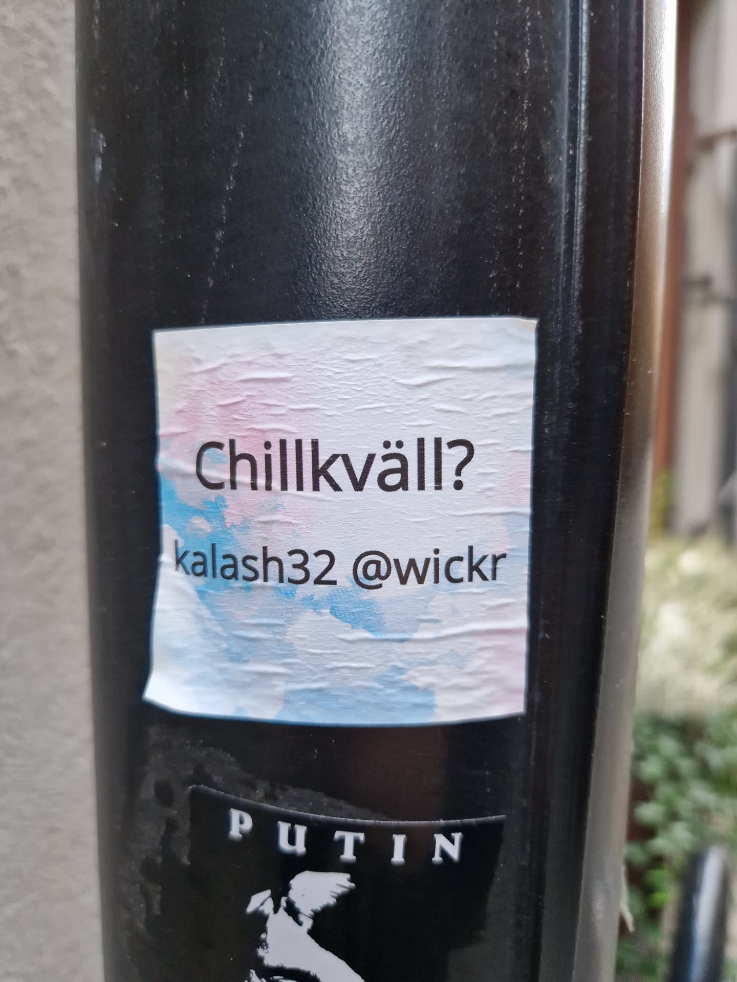 A sticker on a pole with the text "Chillkväll?" and the Wickr handle kalash32. The background of the sticker is a light blue and pink watercolor wash.