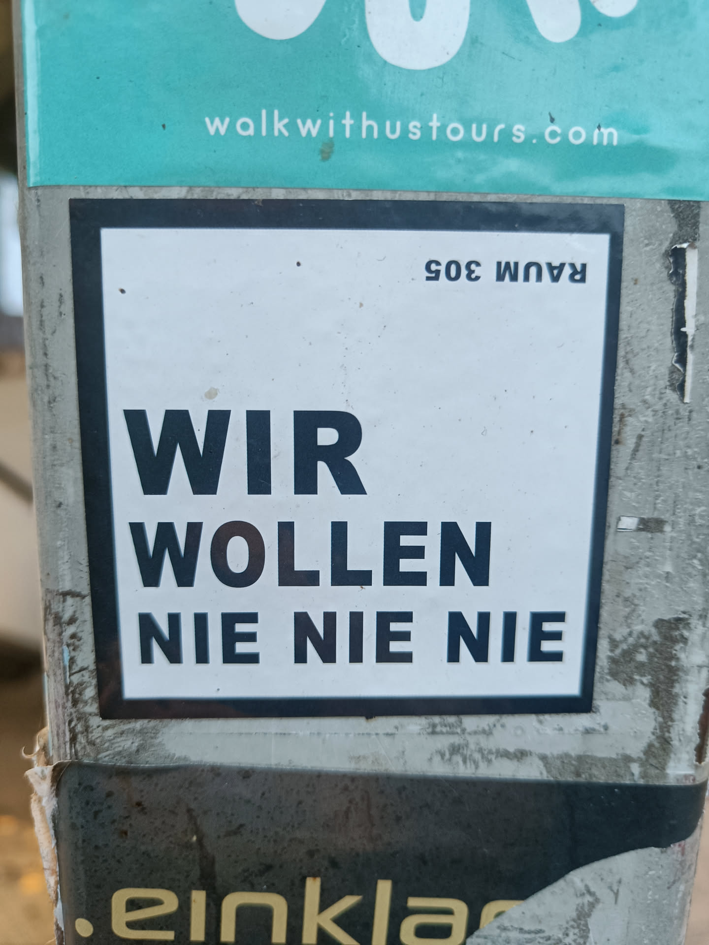 A sticker with the German phrase "Wir wollen nie nie nie" which translates to "We never want never never" in English.  The sticker also has the number "Raum 305" (Room 305) in the top right corner.