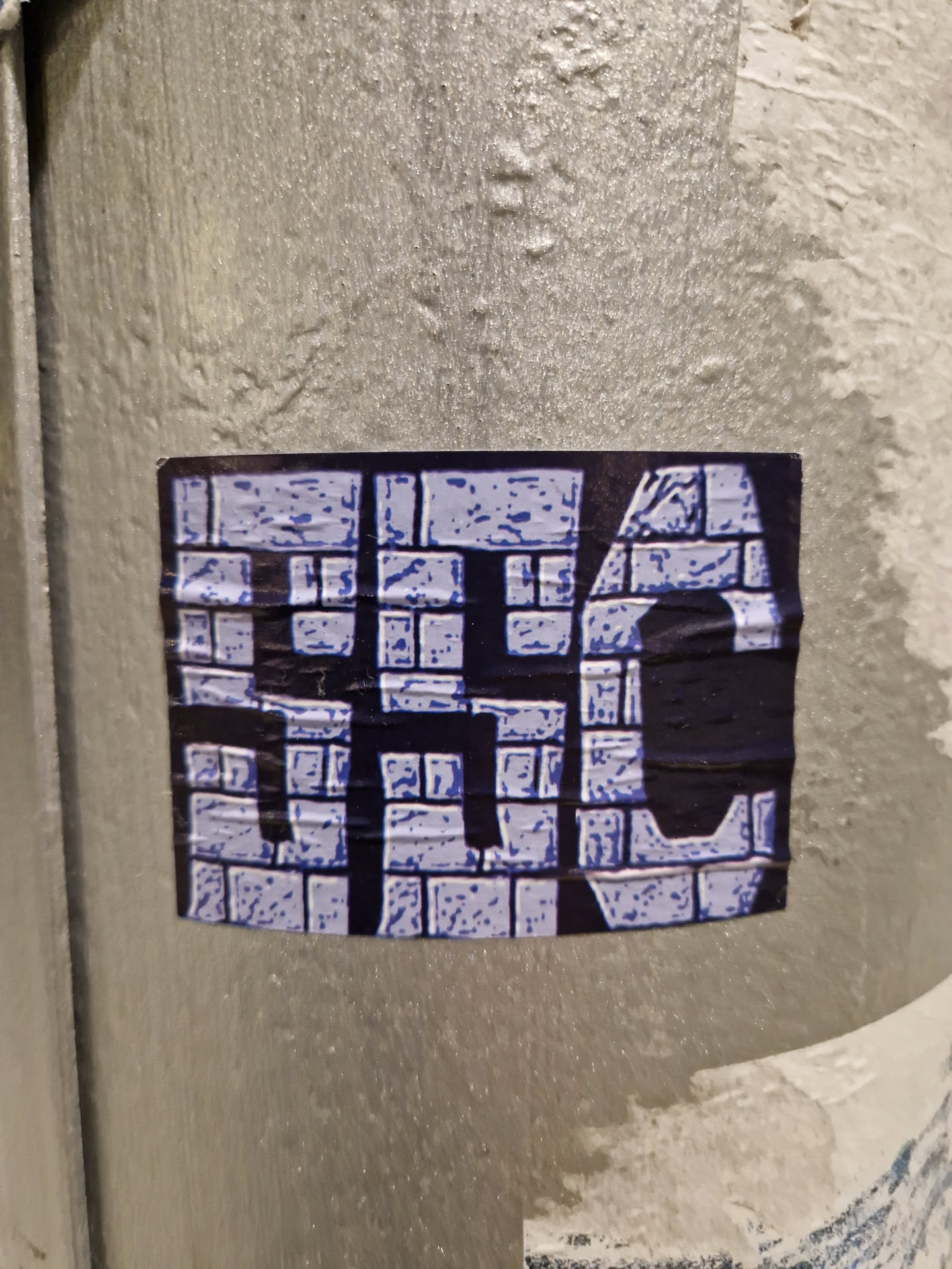 A square sticker with a design resembling a brick wall pattern. The letters 'HSC' are prominently featured in a stylized font within the brickwork.