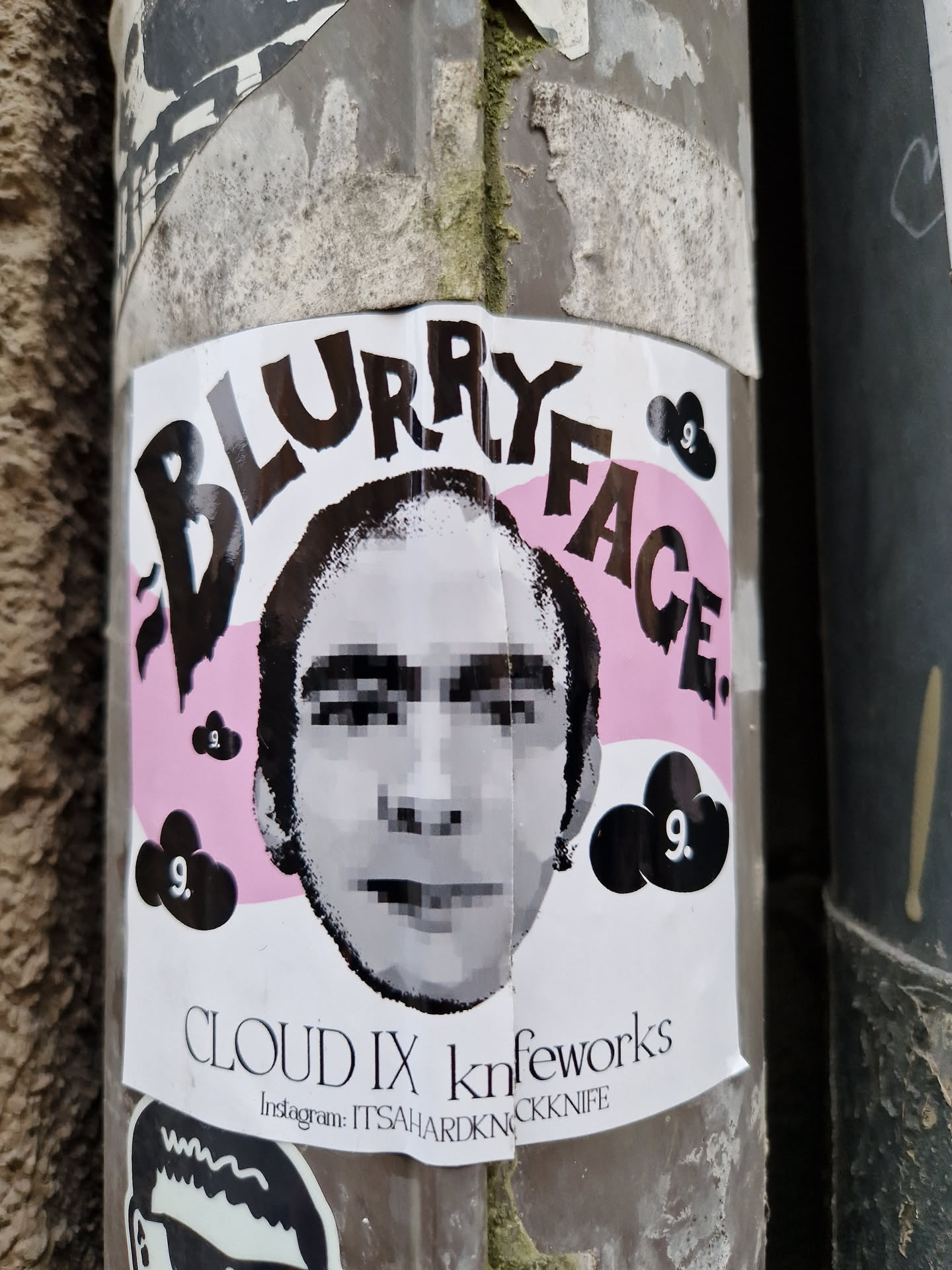 A sticker featuring a pixelated portrait with the words 'Blurry Face' in a bold, stylized font.  The background includes pink and black cloud-like shapes. The artist's Instagram handle is provided at the bottom. 