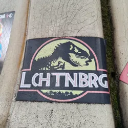 A black sticker with a pale yellow Jurassic Park logo. Instead of the original text, it says LCHTNBRG in a stylized font.