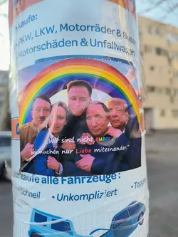 A sticker shows a group of political figures posing intimately under a rainbow. The people included are Hitler, Sahra Wagenknecht, Elon Musk, Vladimir Putin, and Donald Trump. Text on the sticker reads: "Wir sind nicht queer, wir machen nur Liebe miteinander." which translates to "We are not queer, we just make love with each other."