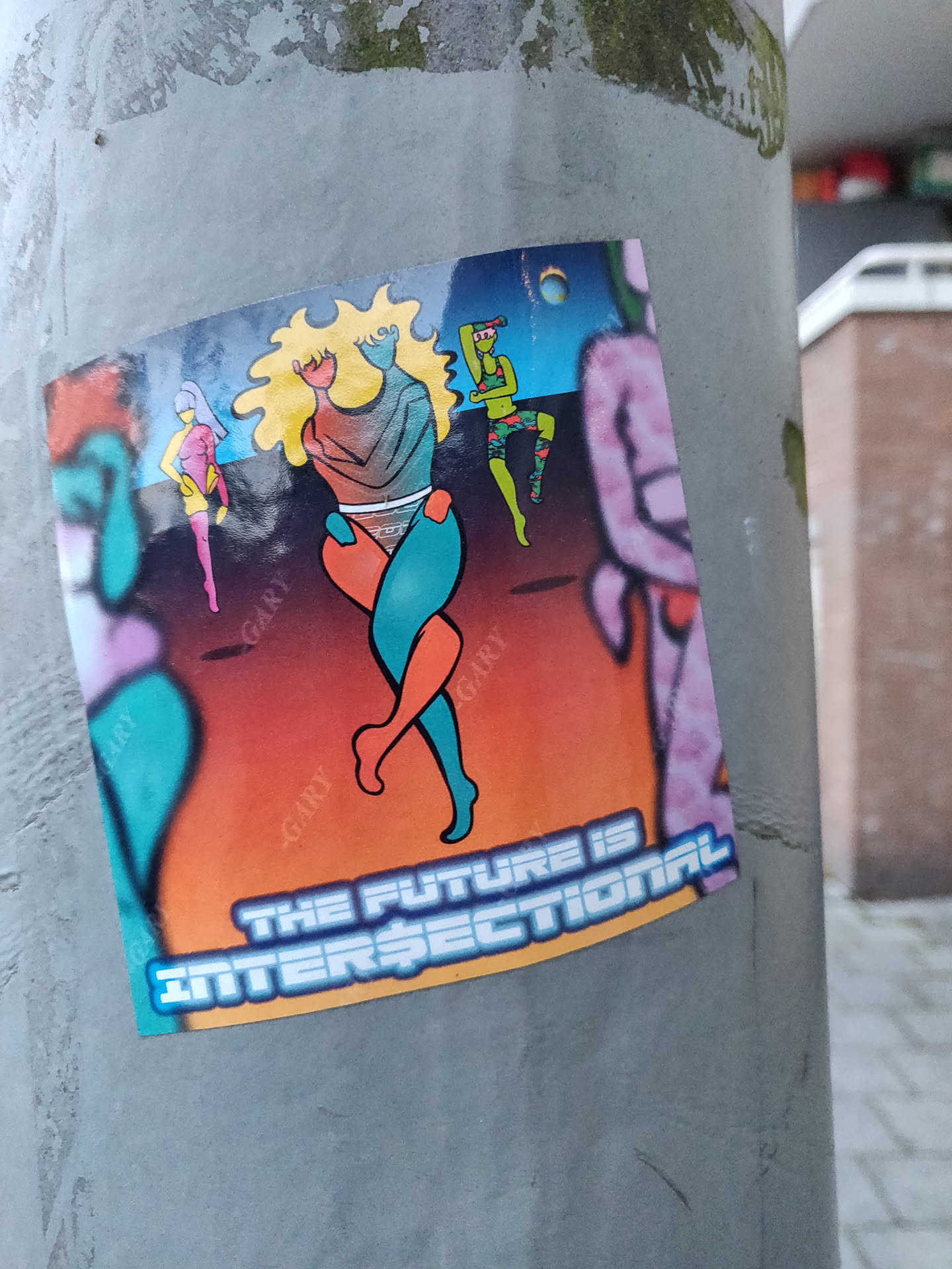 A sticker with a vibrant illustration of stylized figures in a futuristic setting. The main focus is two figures embracing, while other figures are dancing in the background. The sticker has a bold text at the bottom stating "The Future is Intersectional".