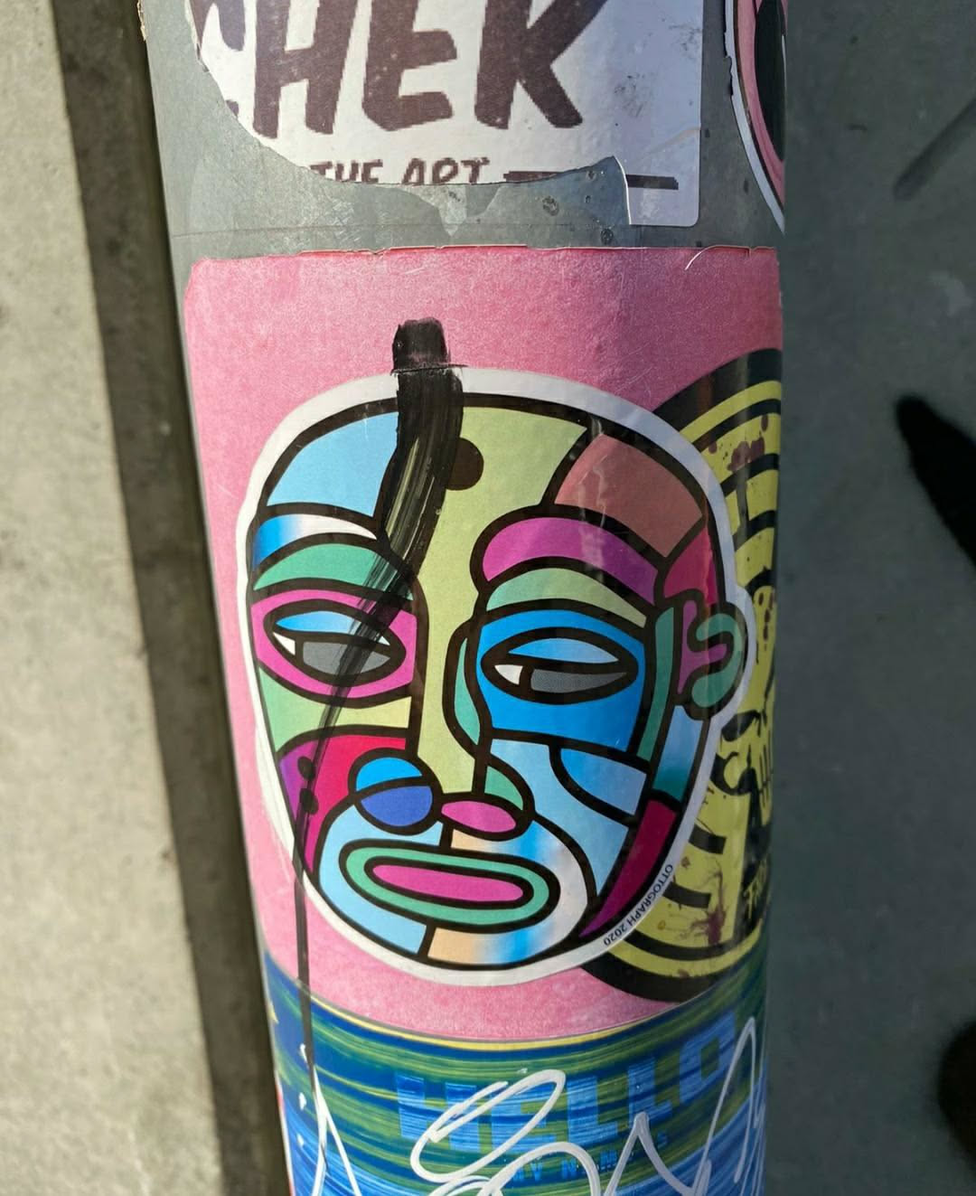 This sticker features a vibrant, geometric design of a face. The colors are bright and bold, creating a striking visual impact. The style is reminiscent of pop art or modern illustration. 