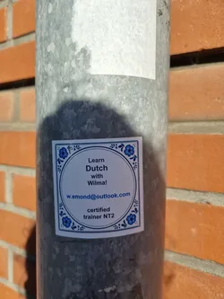 A sticker advertising Dutch language lessons with Wilma.  The sticker features a blue and white design and includes Wilma's email address and certification.