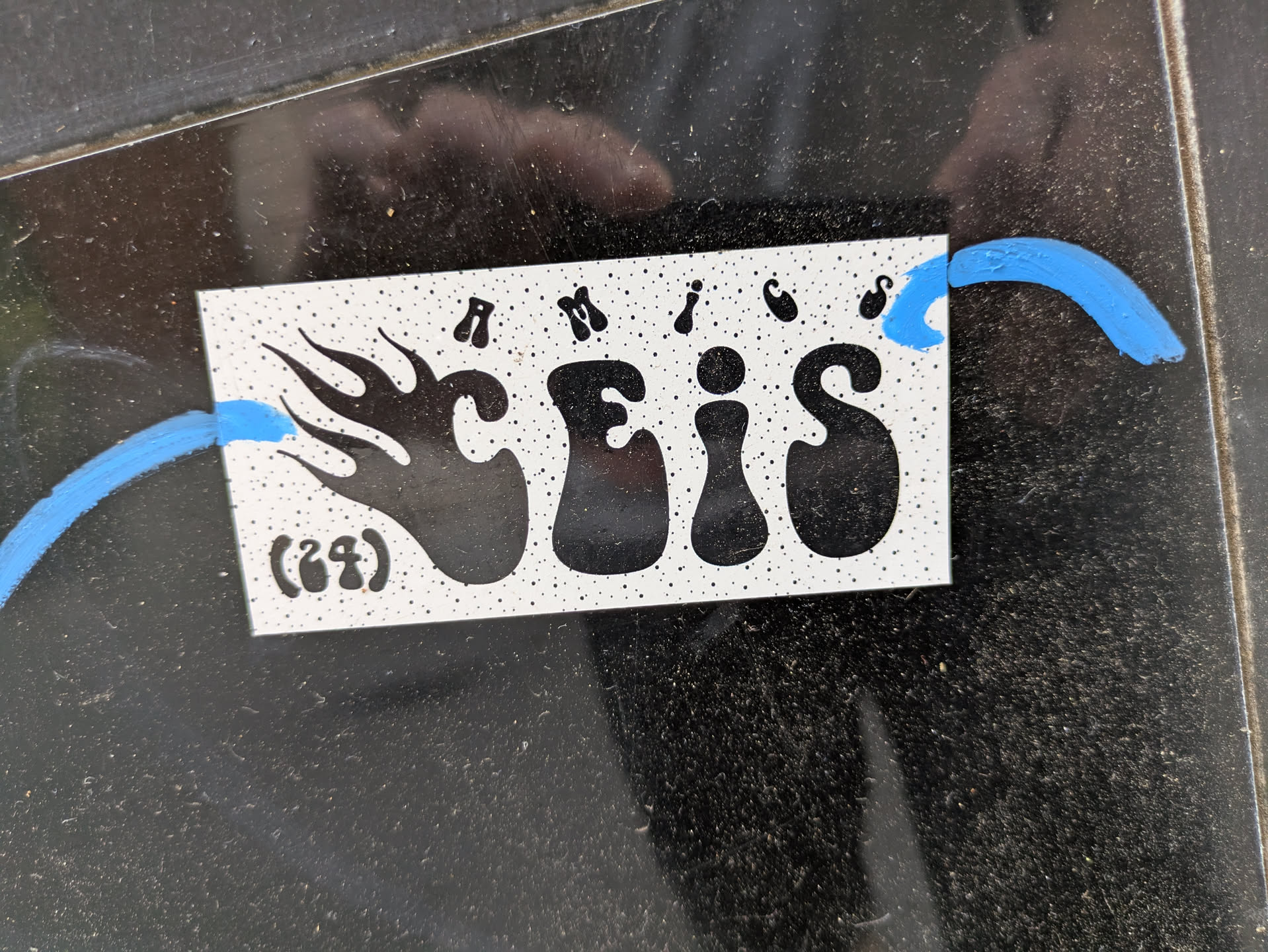 The sticker features the stylized text "SCEIS" with a flame-like design to the left and blue artistic lines extending from either side. The background of the sticker is white with black specks.
