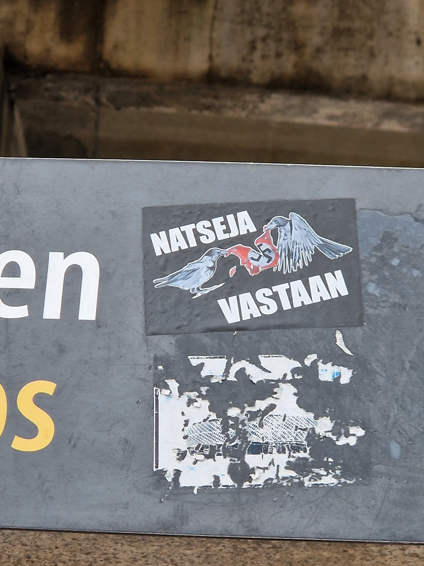 A sticker depicting two crows destroying a swastika. The text on the sticker says "Natseja Vastaan." which translates from Estonian to "Against Nazism".