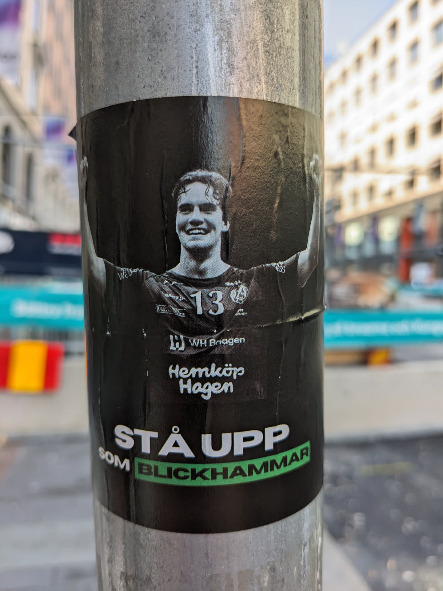 A black and white image of a young man with his arms raised in victory. He is wearing a sports jersey with the number 13. The text at the bottom of the sticker says "Stå upp som Blickhammar", which translates from Swedish to "Stand up as Blickhammar". The Hemköp Hagen logo is visible.