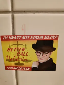 A sticker featuring a person in a black hat and glasses, reminiscent of Saul Goodman from Better Call Saul. The text 'Better Call Holstein' is prominently displayed, along with a phone number '555-HOLSTEIN' and the German phrase 'Im Knast mit einem Bein?' which translates to 'In jail with one leg?'