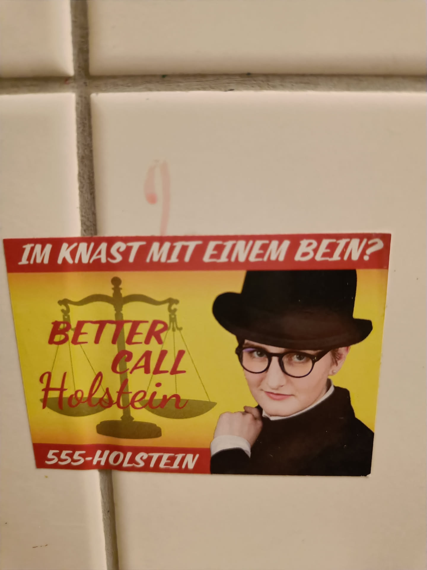 A sticker featuring a person in a black hat and glasses, reminiscent of Saul Goodman from Better Call Saul. The text 'Better Call Holstein' is prominently displayed, along with a phone number '555-HOLSTEIN' and the German phrase 'Im Knast mit einem Bein?' which translates to 'In jail with one leg?'