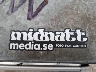 Black and white sticker with the text Midnatt media.se and the words Foto Film Content underneath. The text Midnatt uses a stylized font.