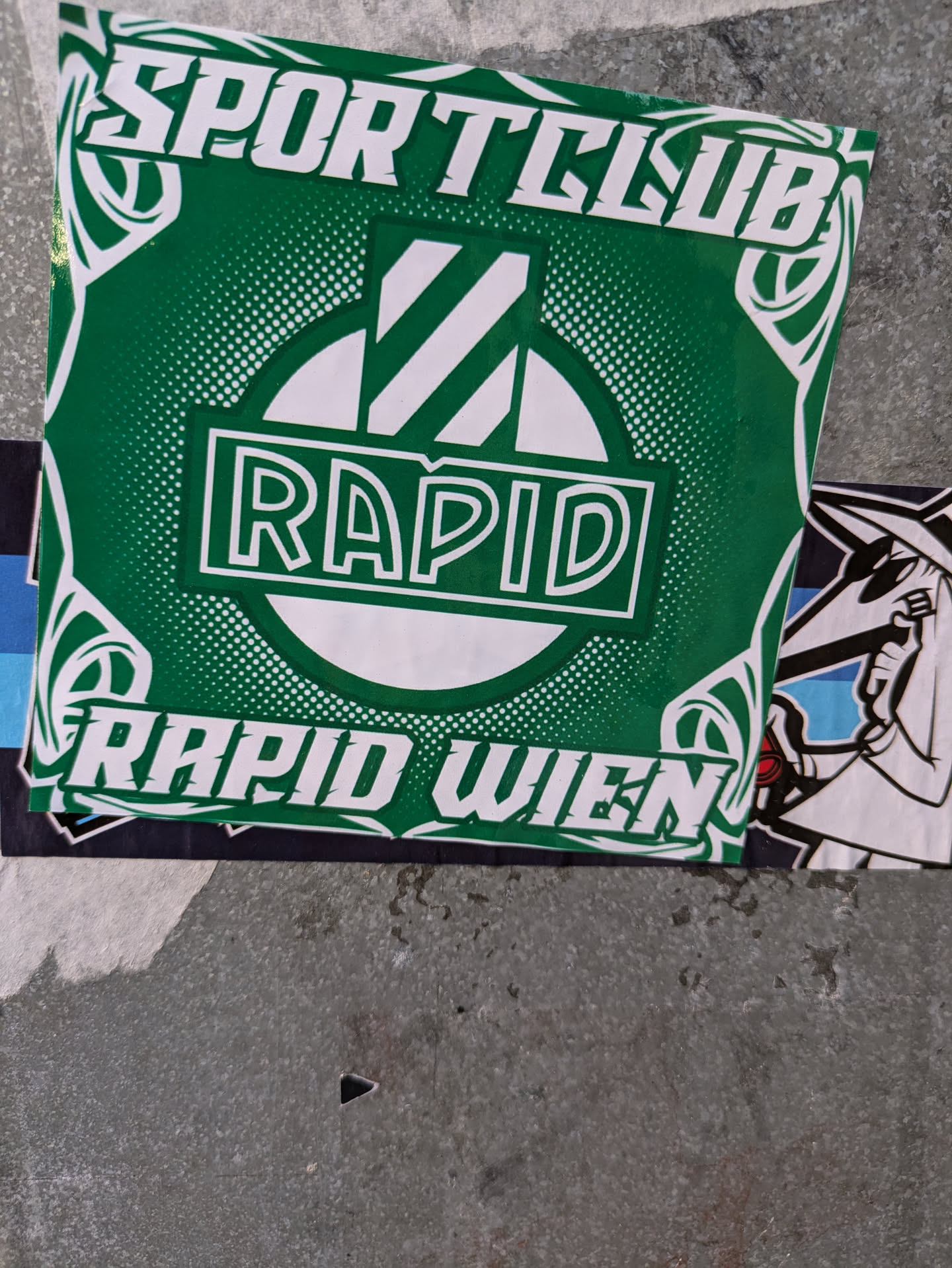 Green and white sticker with the Rapid Wien logo. It says "Sportclub" at the top and "Rapid Wien" at the bottom. The logo is a circle with white and green stripes inside it and the word "Rapid" in the center.