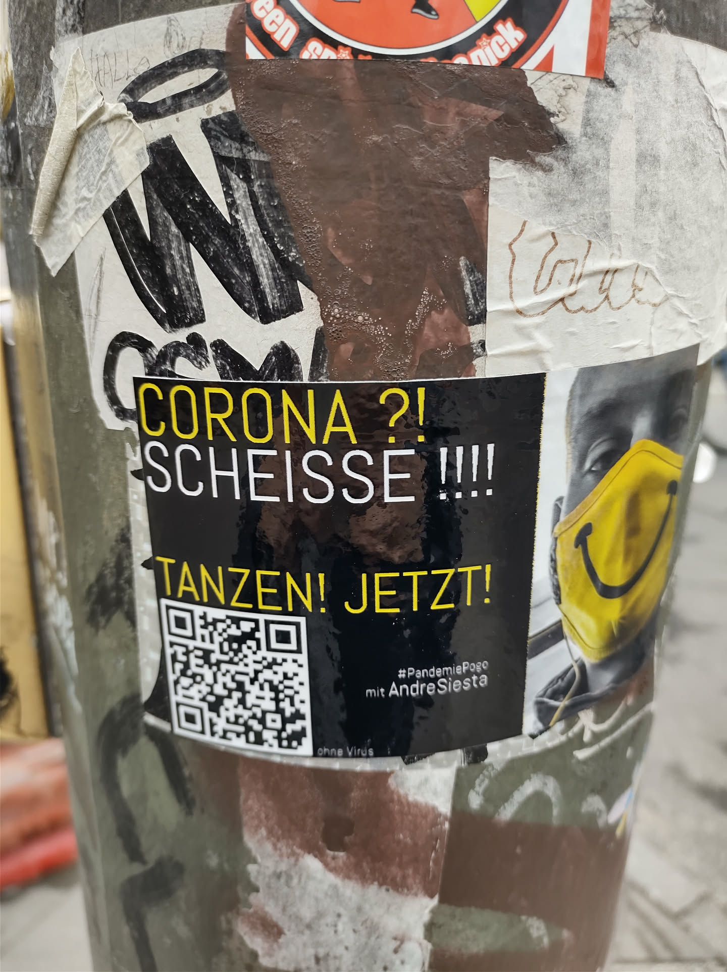 A sticker expressing frustration with the Corona pandemic and encouraging dancing. It features a QR code and a smiley face mask.  The text says: "CORONA?! SCHEISSE!!! TANZEN! JETZT!" which translates to "Corona?! Shit!!! Dance! Now!"