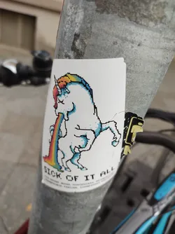 Street sticker A pixel art sticker of a unicorn throwing up a rainbow. The text at the bottom says "Sick of it all".