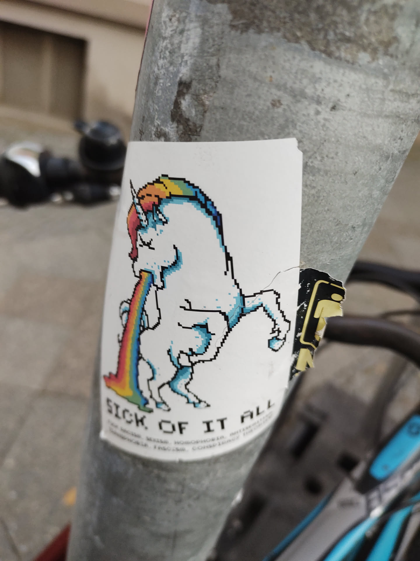 A pixel art sticker of a unicorn throwing up a rainbow. The text at the bottom says "Sick of it all".