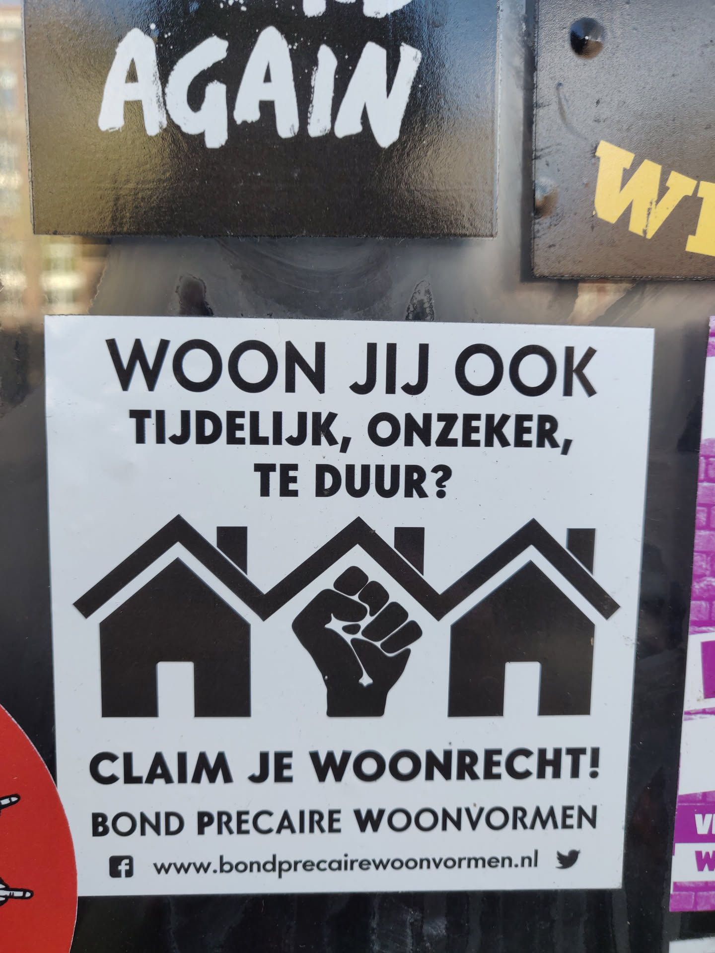 Sticker from Bond Precaire Woonvormen, advocating for housing rights.  It depicts three houses with a raised fist in the center, symbolizing collective action. The sticker includes a website and social media links.