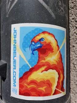 A vibrant sticker featuring a stylized eagle rendered in shades of orange and yellow, set against a blue background with yellow rays. The text 'JOHNBELIER.COM' is visible on the sticker, along with a small logo.