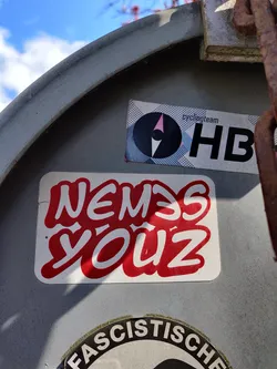A red and white sticker with graffiti-style lettering that says "Nemesis Youz".