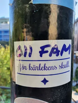 A white sticker with blue text on a dark pole. The text says "011 Fam - för kärlekens skull." which translates to "011 Fam - for the sake of love."