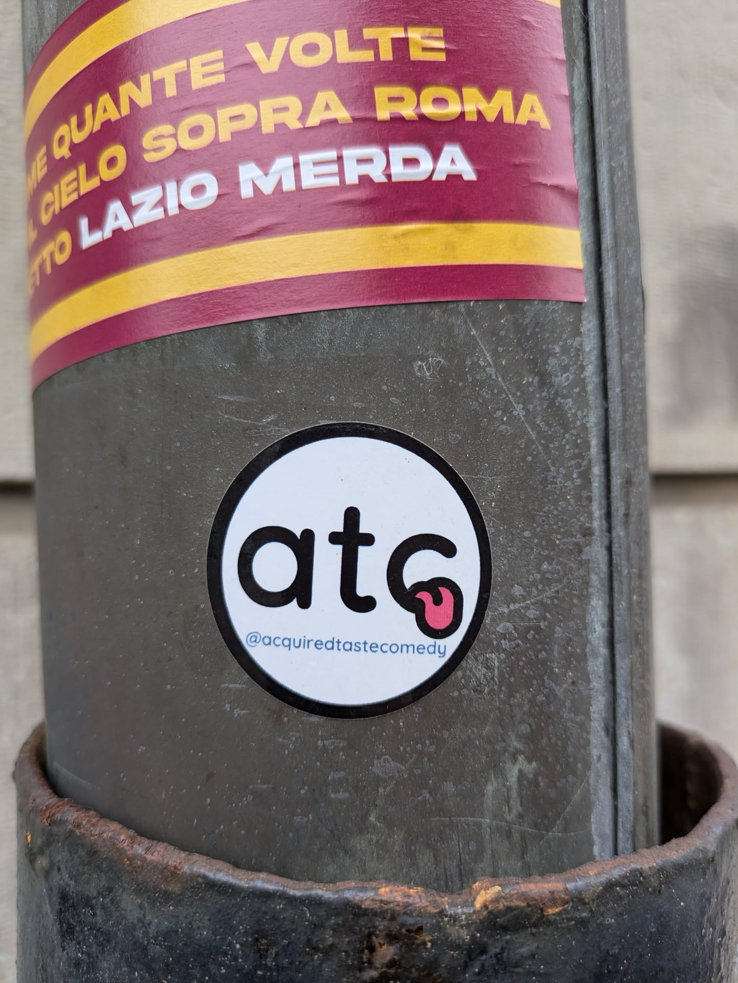 Round white sticker with the letters atc and a tongue emoji.  The Instagram handle @acquiredtastecomedy is printed below the logo.