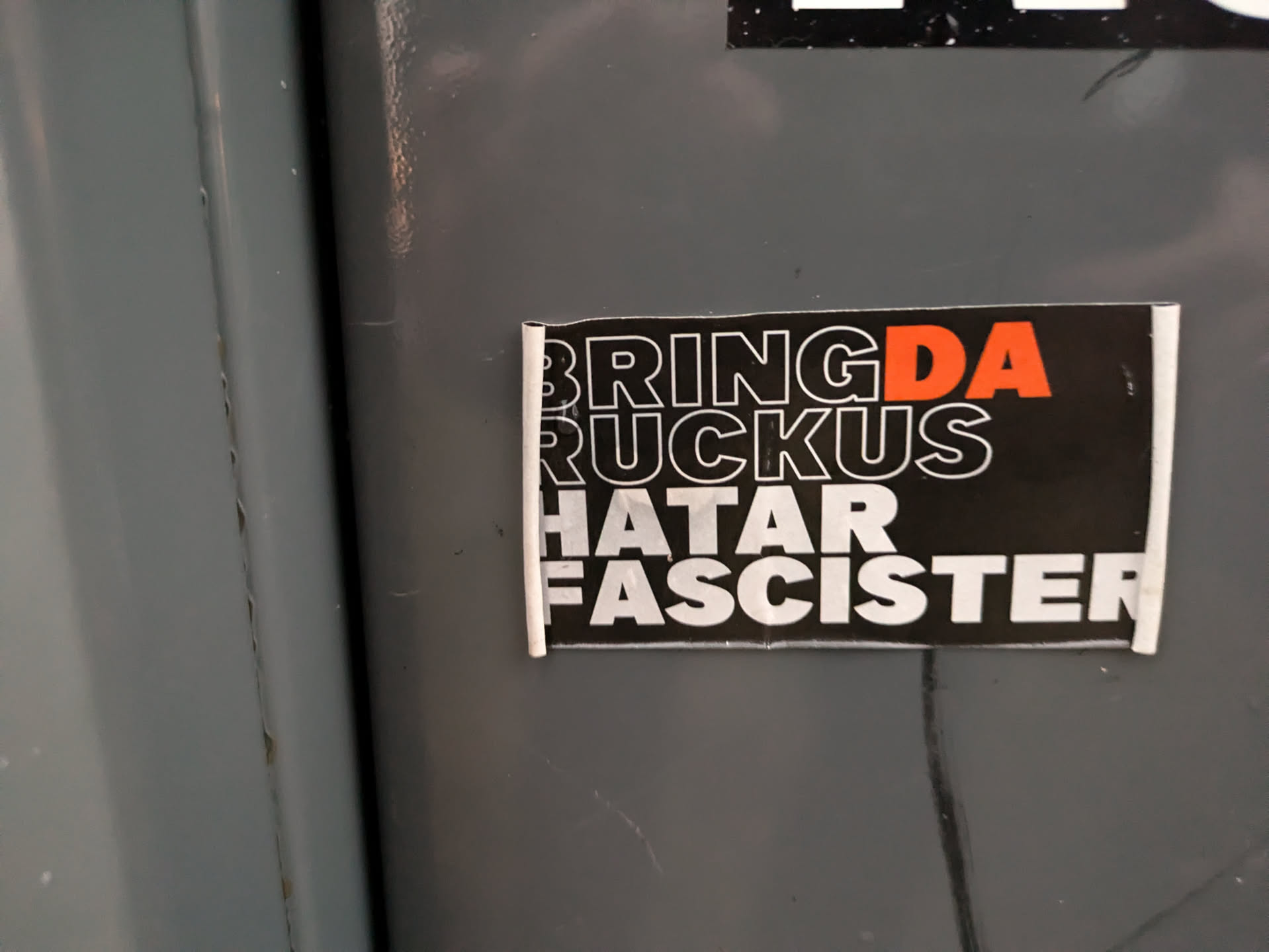 A black and white sticker with orange accents. The text on the sticker says "Bring Da Ruckus Hatar Fascister".