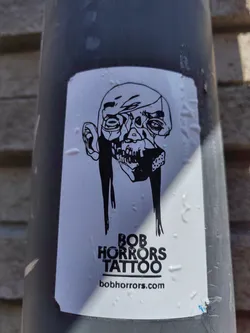 A black and white sticker featuring a skull-like face with long hair, and the text "BOB HORRORS TATTOO" and website address bobhorrors.com.
