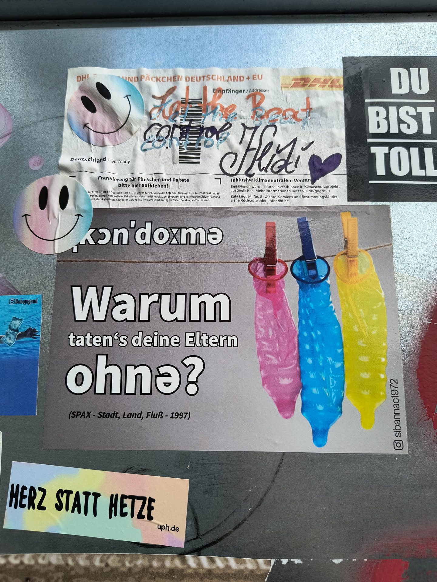 A sticker with a provocative question in German, accompanied by an image of three condoms hanging on a clothesline. The overall style is simple and direct.