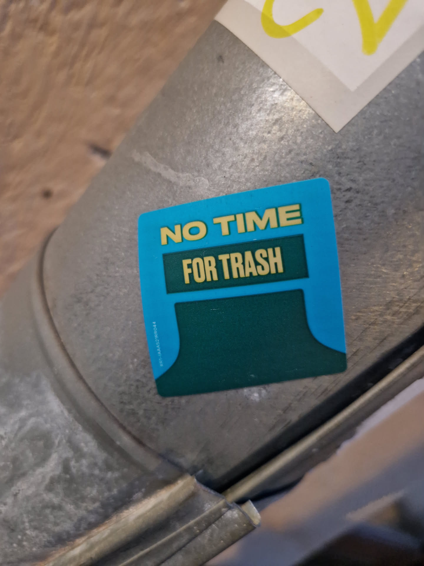 A teal and dark green sticker with the text "NO TIME FOR TRASH" on a metal surface. 