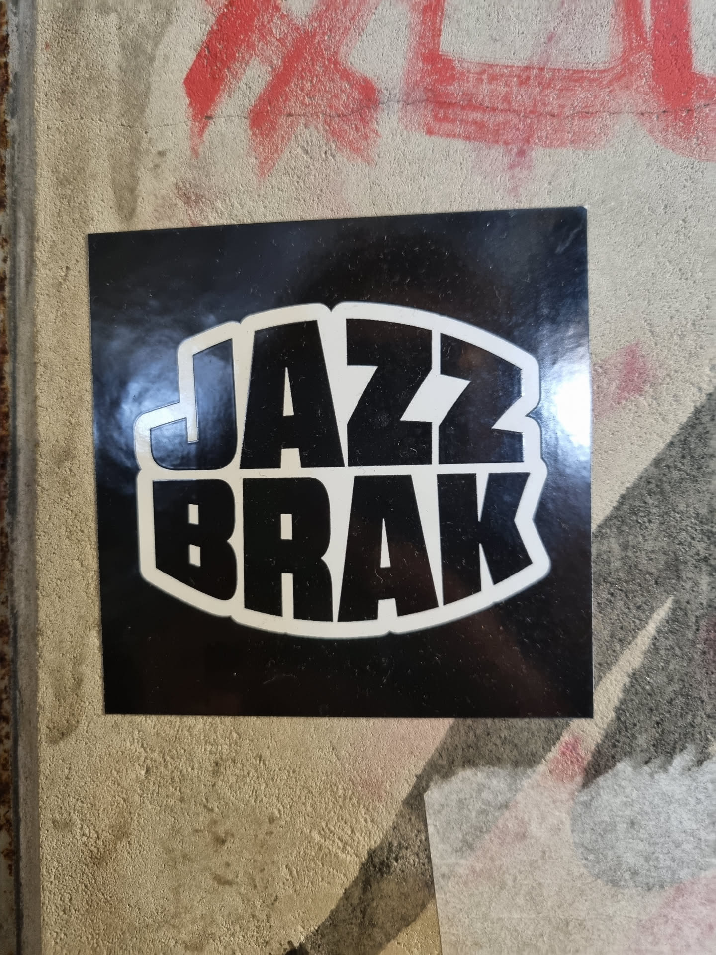 A black and white sticker with the words JAZZ BRAK in a stylized font. The text is bold and set within a circular shape.  The sticker has a glossy finish.