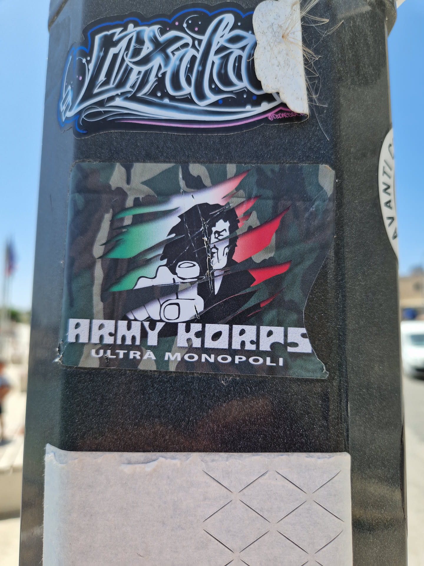 A sticker featuring a stylized illustration of a man with a gun, set against a camouflage background with Italian flag colors. The text "Army Korps Ultra Monopoli" is prominently displayed.