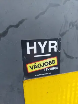 A black and yellow sticker advertising Vägjobb, a car rental service in Sweden.  The text on the sticker says "HYR" (Rent), "VÄGJOBB", "I SVERIGE" (In Sweden), and includes a website address.