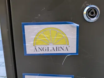 A sticker featuring a yellow lemon slice graphic and the text ÄNGLARNA. The sticker has a simple design with a blue border.