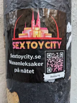 A sticker advertising Sextoycity.se, an online sex toy store. The sticker features an illustration of a cathedral and the text 'Sextoycity.se' and 'Vuxenleksaker på nätet' (Adult toys online in Swedish). It also includes a QR code.