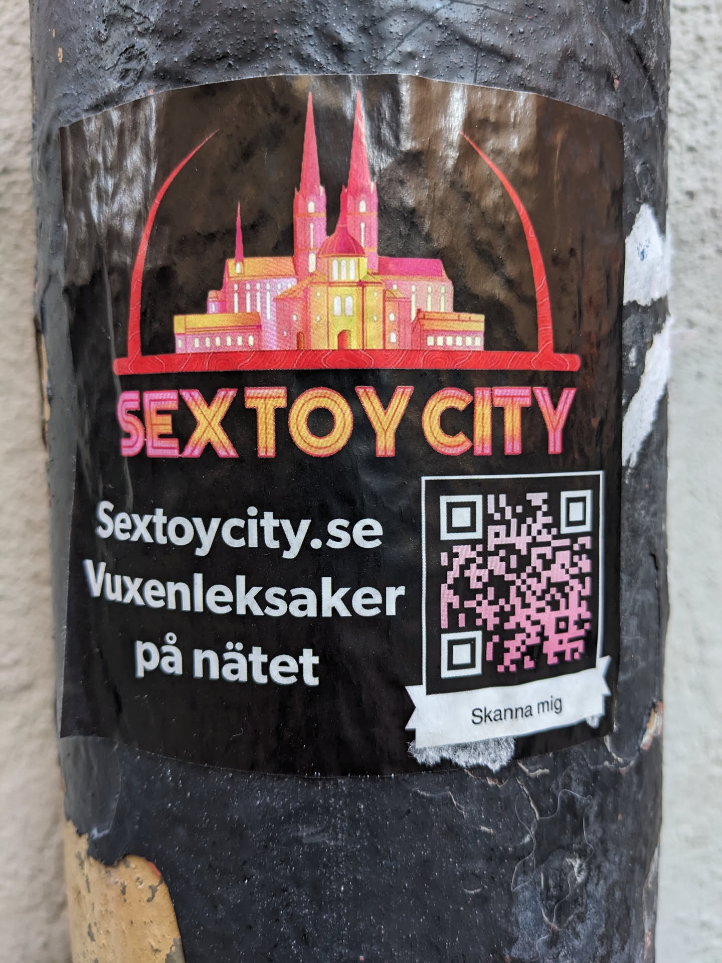 A sticker advertising Sextoycity.se, an online sex toy store. The sticker features an illustration of a cathedral and the text 'Sextoycity.se' and 'Vuxenleksaker på nätet' (Adult toys online in Swedish). It also includes a QR code.