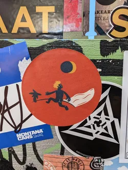Round sticker with an orange background featuring a minimalist illustration of a person surfing. The illustration is in black and the background is a gradient orange color. The sun and the moon are also illustrated in the background. 
