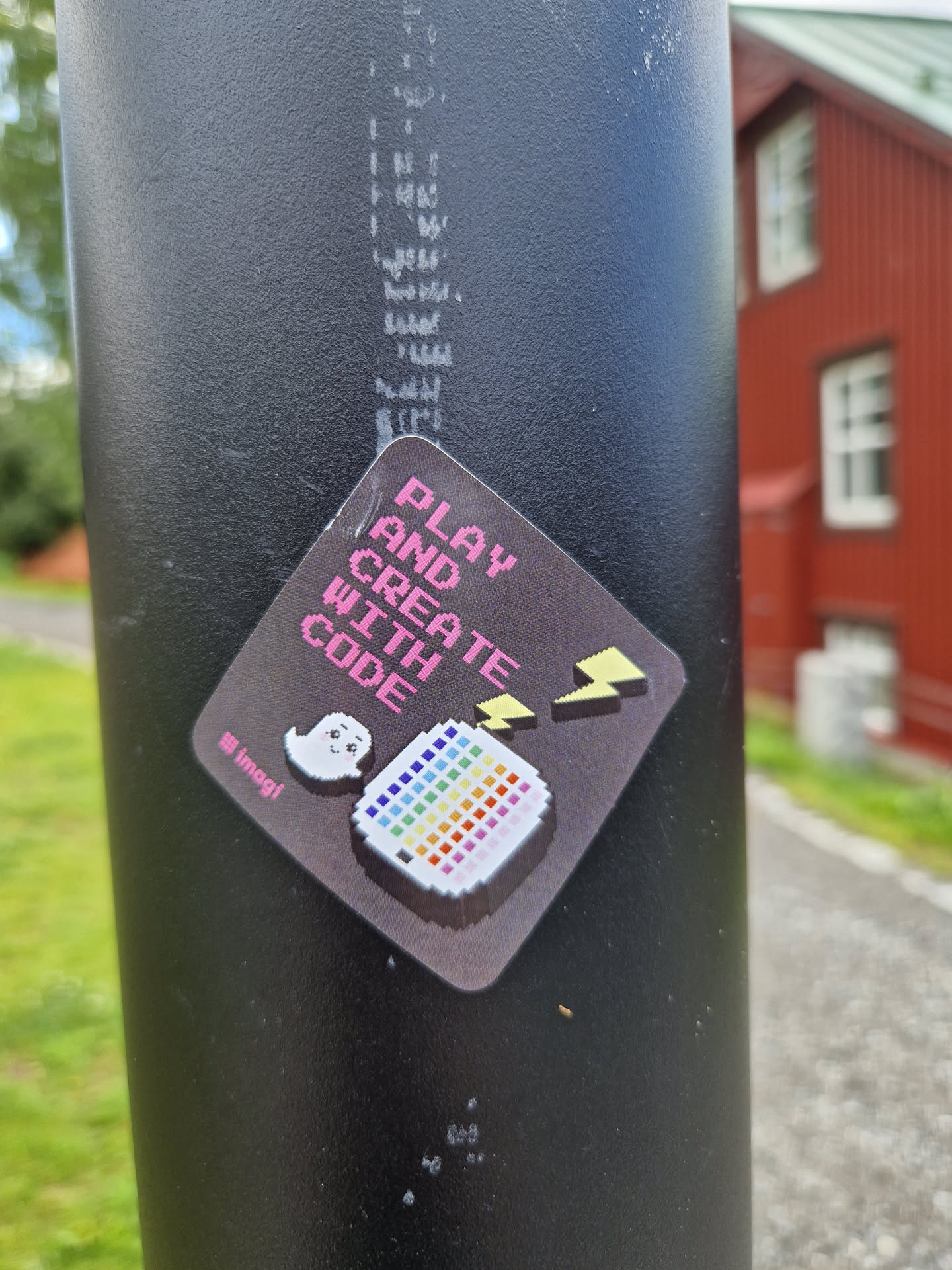 A sticker with a pixel art design featuring a rainbow-colored palette and a cute ghost. The text on the sticker says "PLAY AND CREATE WITH CODE".