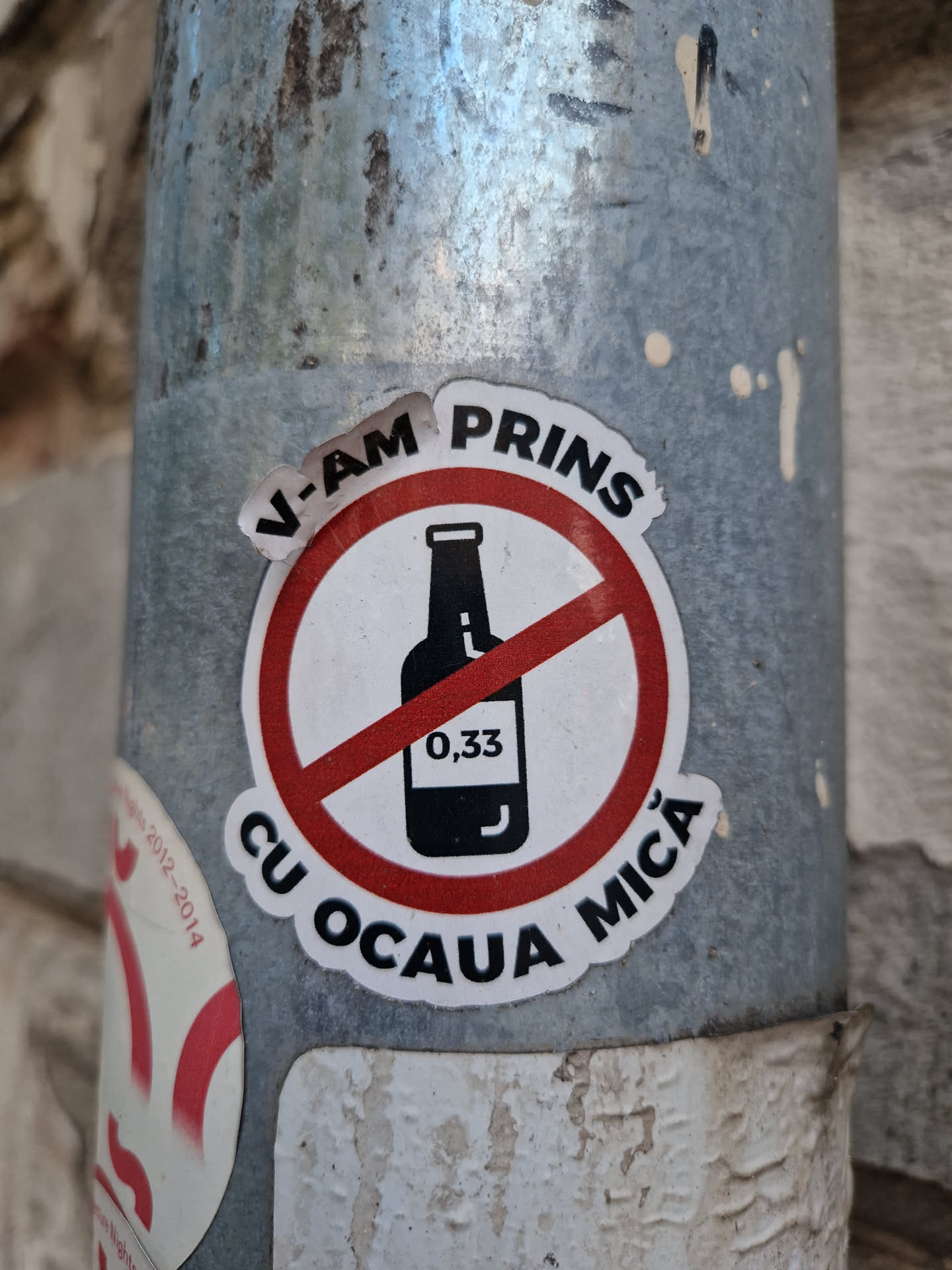 A sticker depicting a bottle with a red circle and line through it, with text in Romanian. It translates to "I caught you red-handed!" and likely refers to catching someone drinking alcohol illegally or underage.