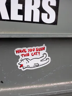 A white sticker with a cartoon cat lying on its back with its tongue sticking out, asking "HAVE YOU SEEN THIS CAT?"