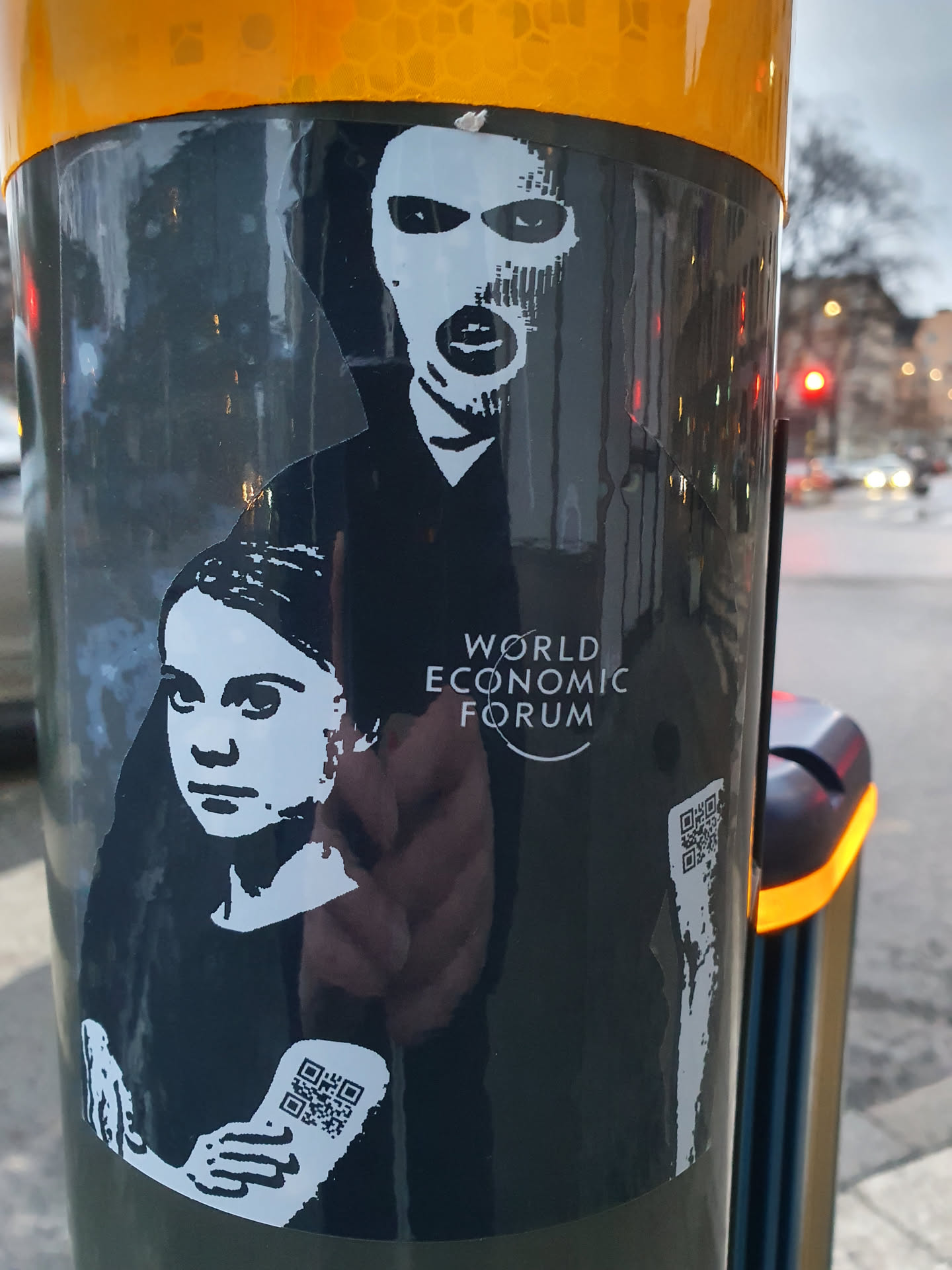 Sticker featuring Greta Thunberg and Guy Fawkes with the text 'World Economic Forum'.  Two QR codes are present on the sticker. The sticker appears to be a form of political commentary or protest.