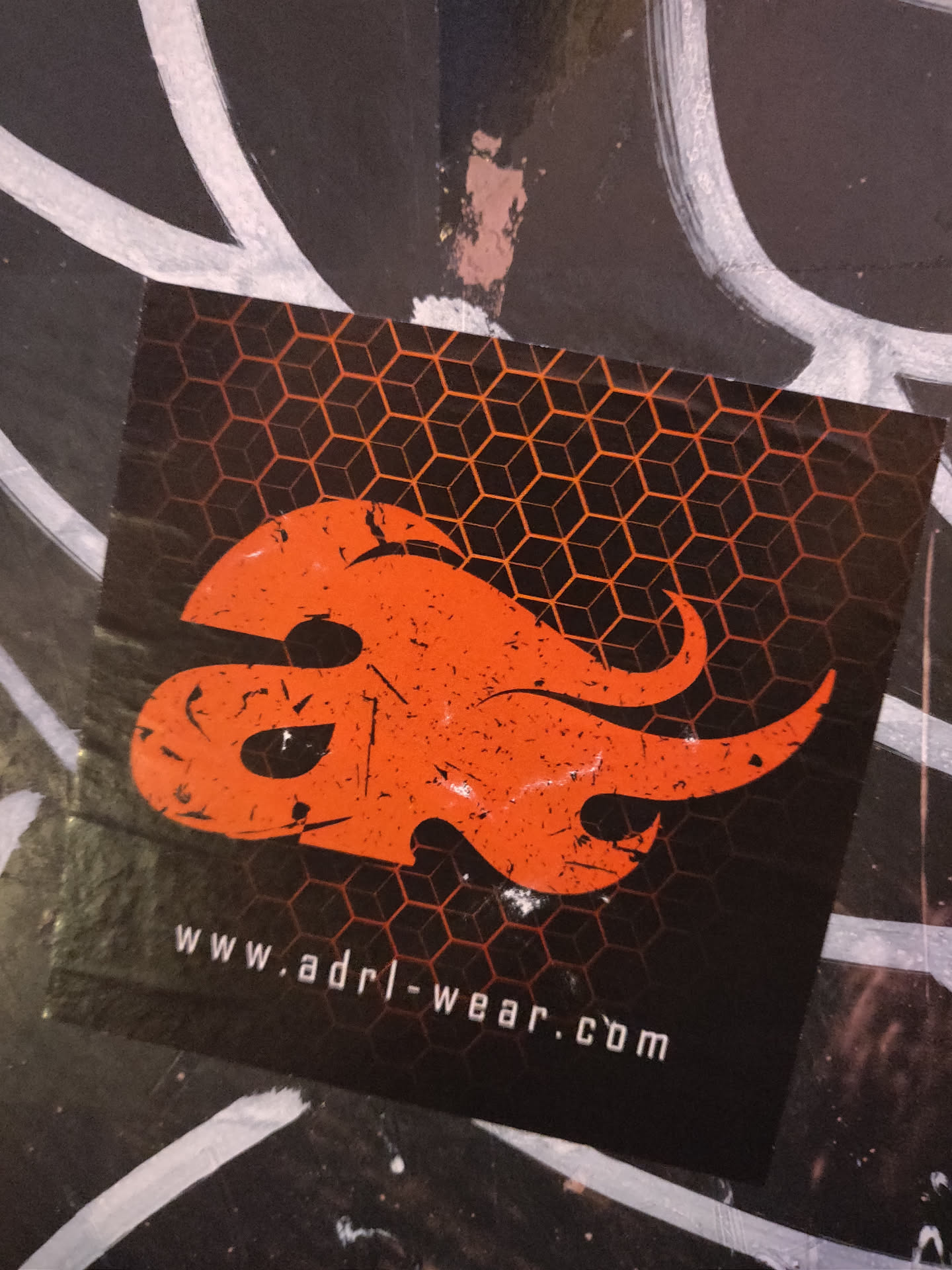 A black and orange sticker with a stylized flame logo and a honeycomb background.  The website address www.adrl-wear.com is printed at the bottom.