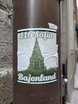 A sticker featuring an illustration of a church with the address "116 Sofia" and the name "Bajenland" written below it. The style is vintage-inspired, with a faded color palette and a slightly worn look.