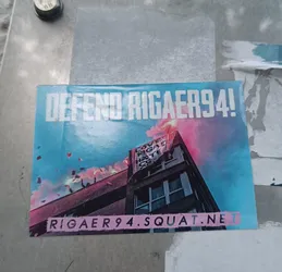 Sticker supporting Rigaer94 squat. The sticker shows a building with a banner and flares. The text on the banner is partially visible and says something about love and hate.  The website address rigaer94.squat.net is shown at the bottom.