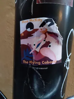A sticker featuring abstract artwork with two figures. The text 'Moa McKay' and 'The Flying Cabaret' is visible. The style is reminiscent of modern art.