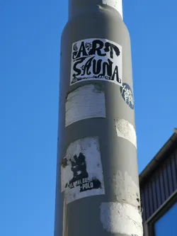 The central sticker is a rectangular, black-on-white design featuring the words 'ART SAUNA' in a highly stylized, illustrative font. The letters of 'ART' are intricately designed, with the 'A' incorporating a flame or smoke motif and the 'T' forming a silhouette of a figure. The letters of 'SAUNA' have a fluid, organic, almost steam-like or wavy appearance. Below the 'S' in 'SAUNA', a small, detailed illustration of a sauna bucket and ladle is visible. The overall aesthetic is a blend of bold typography and intricate line art, giving it a distinctive, somewhat whimsical, and dark graphic novel feel.