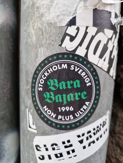 Round black and green sticker with the text "STOCKHOLM SVERIGE" on the top and bottom, "Bara Bajare" in the center, and "1996 NON PLUS ULTRA" below it. The text is written in a stylized font.