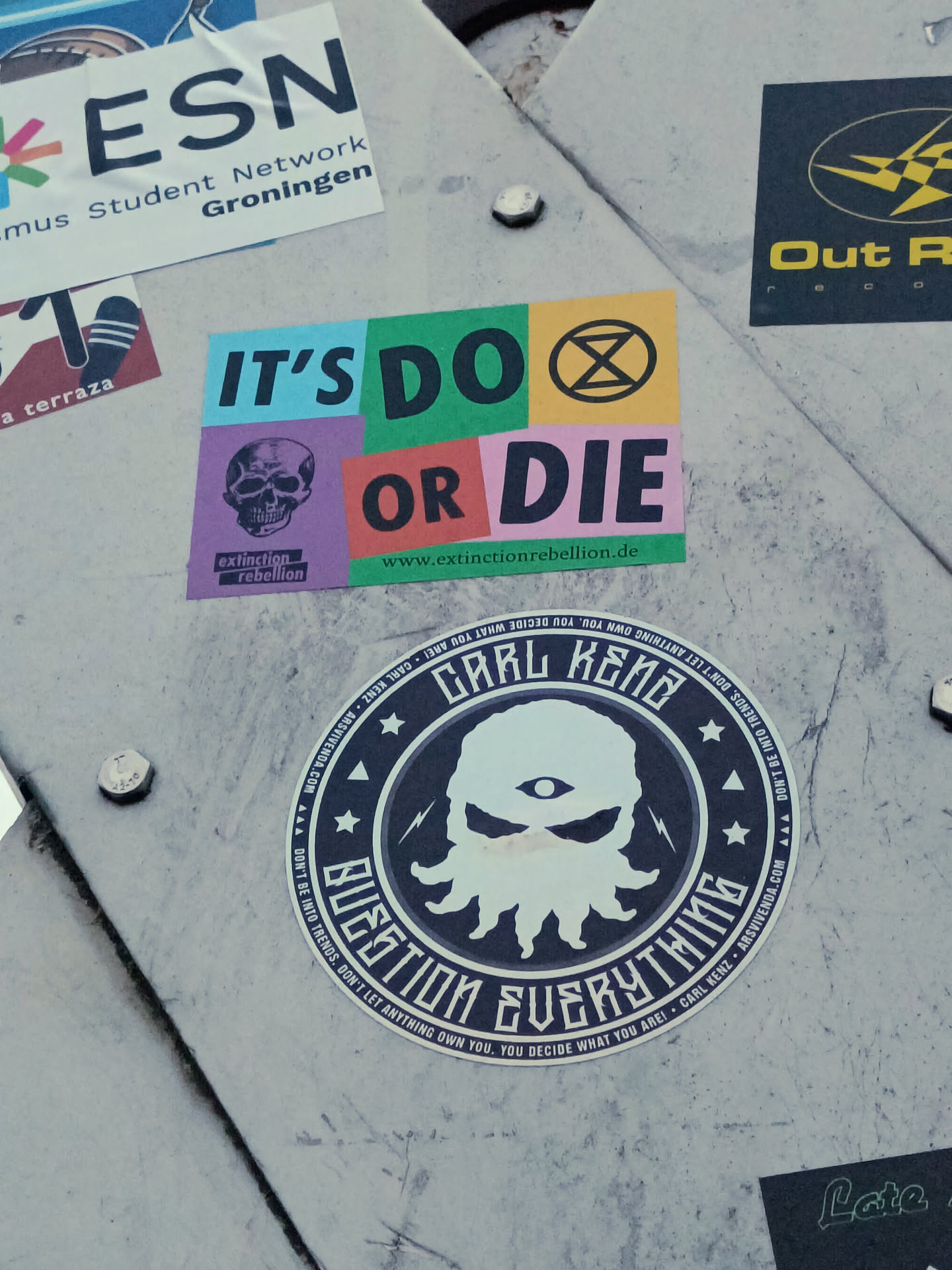 A round sticker featuring a stylized octopus with one eye, surrounded by text that reads "Carl Keno" and "Question Everything". The background is dark gray/black with white text and imagery. The style is dark, edgy, and graphic. 