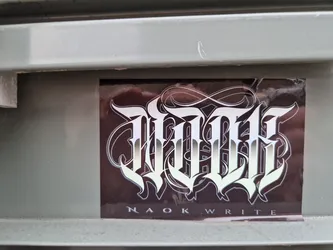 A sticker with a stylized logo of the text "NAOK WRITE" in silver on a dark background.