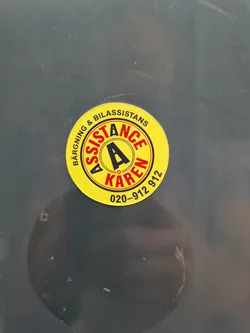 Yellow and red round sticker with the text: "BÄRGNÄNG & BILASSISTANS ASSISTANCE ÄKAREN 020-912 912".